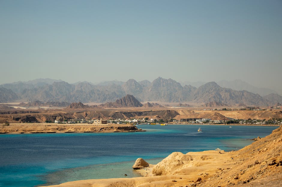 Panoramic view of a coastal town with turquoise waters and rugged mountains in the background.