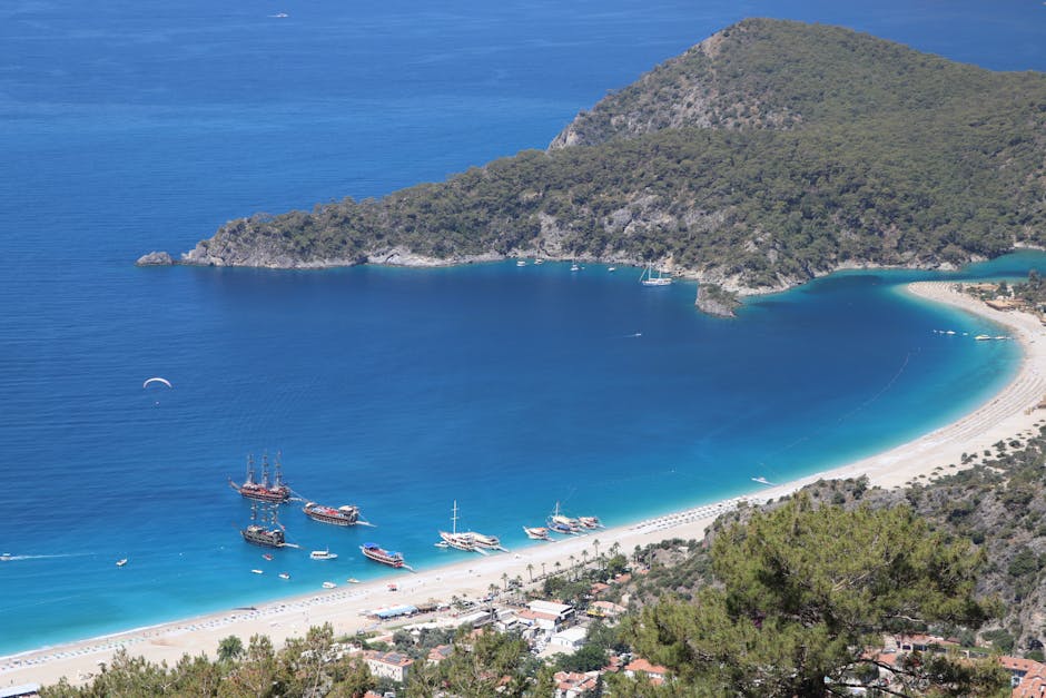 Aerial shot of a beautiful bay with boats and sandy beach, surrounded by lush greenery.