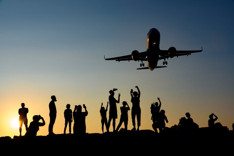 A dynamic silhouette of people photographing an airplane during a vibrant sunset.