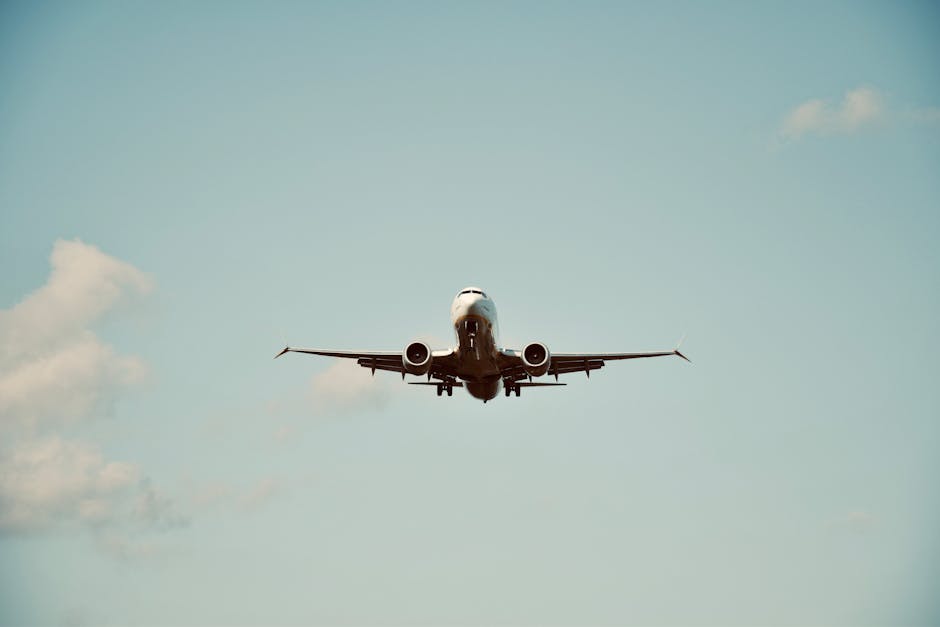 A commercial airplane in flight against a clear blue sky, representing air travel and transportation.